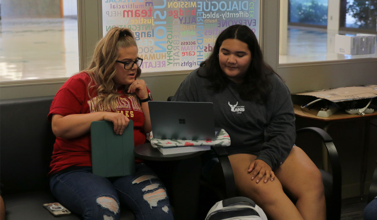 Two students work on a lap top together wearing YVC shirts. 