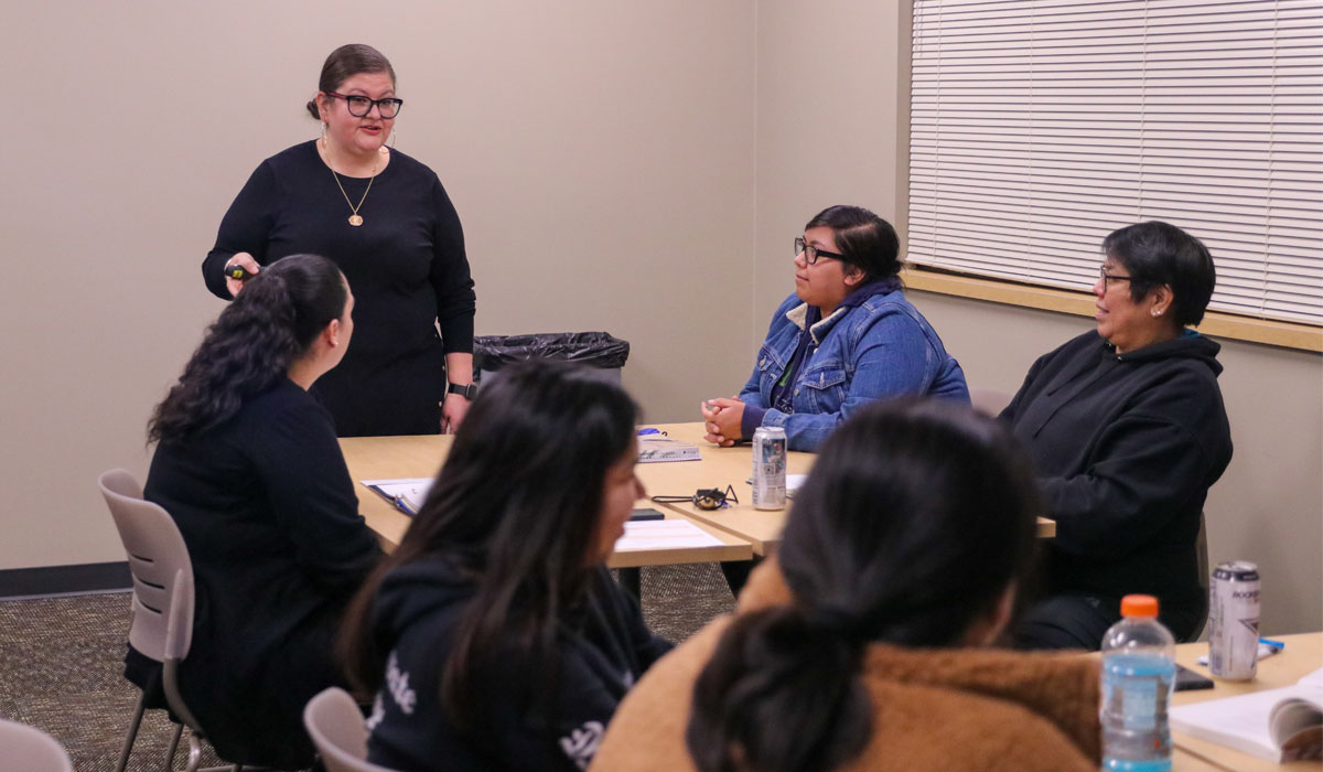 Instructor speaks to a table of students during class. 