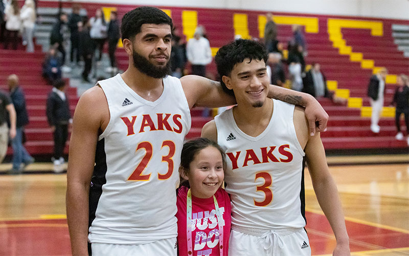 Jose Brown poses with teammate and fan on basketball court