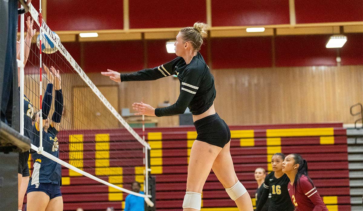 Yakima Valley College volleyball players spikes ball