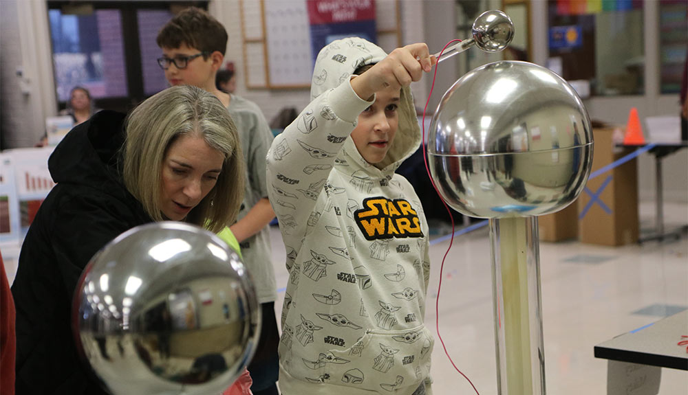 Young boy plays with Van de Graaff generator