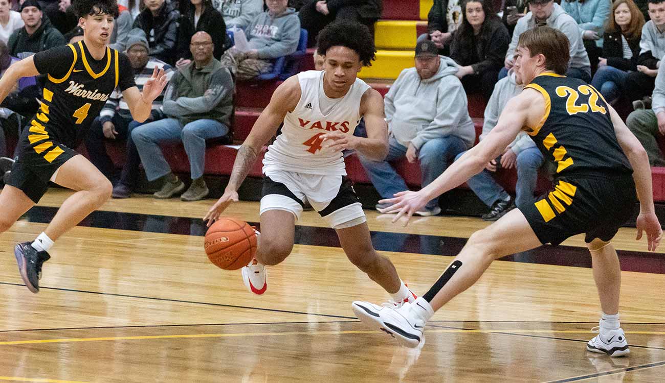 Male basketball player dribbles past defender