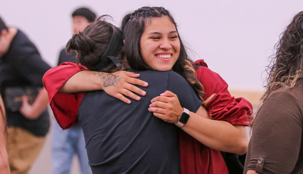 Graduate hugs another individual