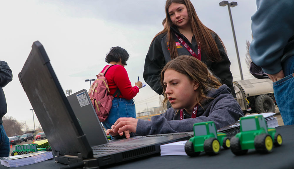 Student at laptop outside while another student looks over shoulder