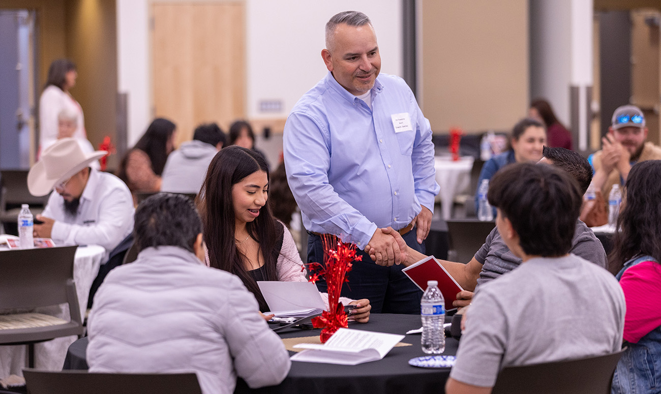 Ernesto Sanchez shakes hands with students before the Foundation ceremony begins