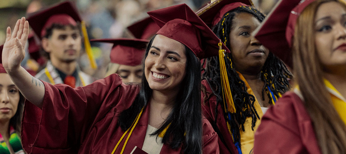 YVC Student waves to crowd in her cap and gown during the YVC Commencement Ceremony. 