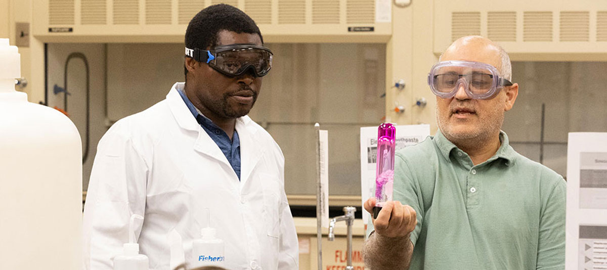 Student pictured with professor during a lab. 