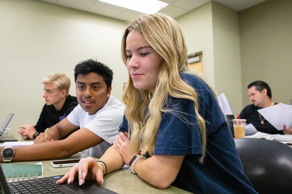 Students look at a computer in class