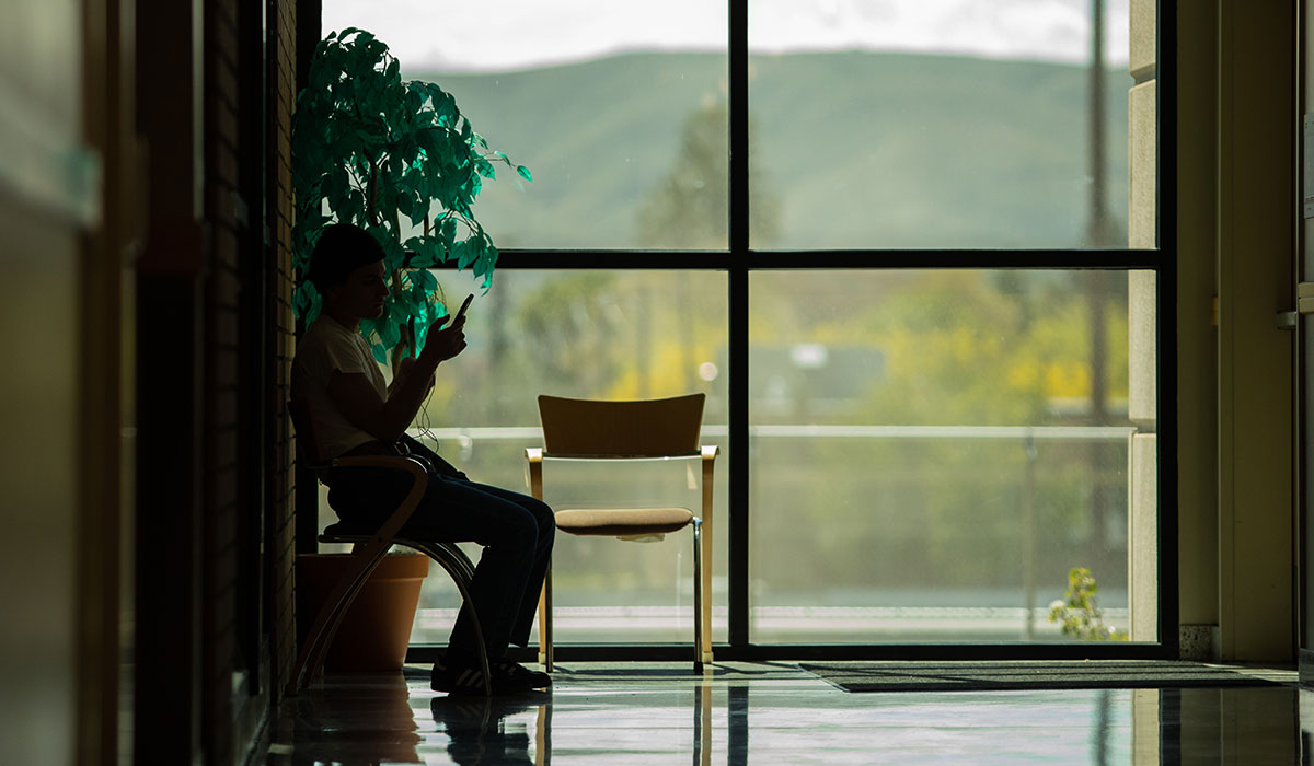 A student looks at his phone in the Deccio Building