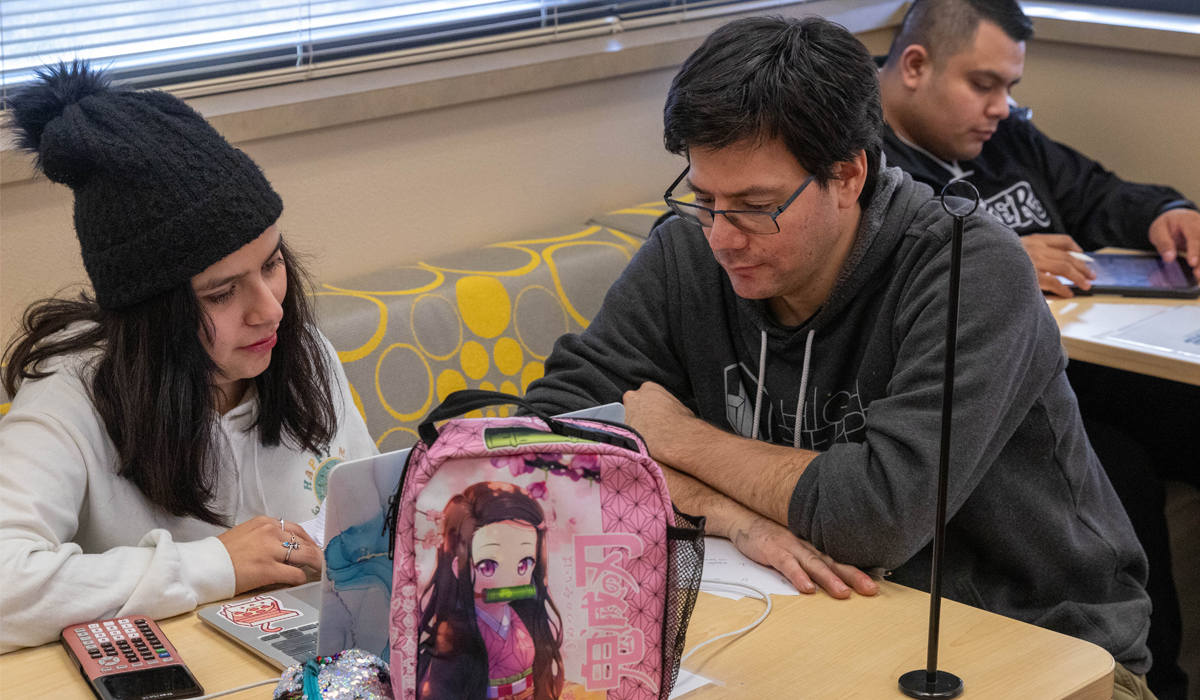 Student sits with tutor working on homework. 