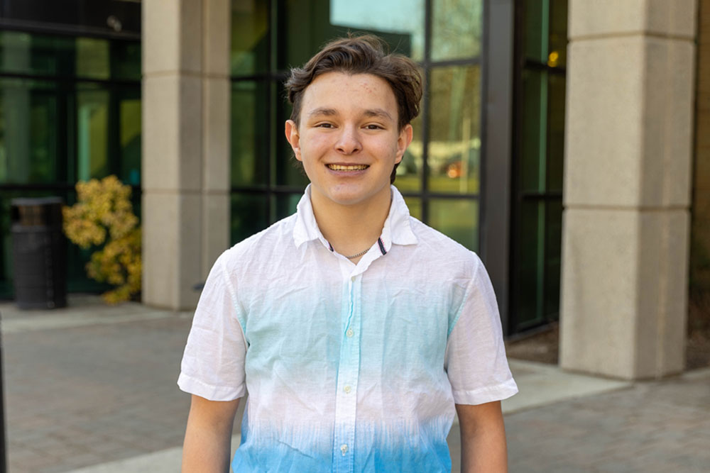 Andrew Escamilla poses for student story profile picture in front of a academic building on the YVC campus. 