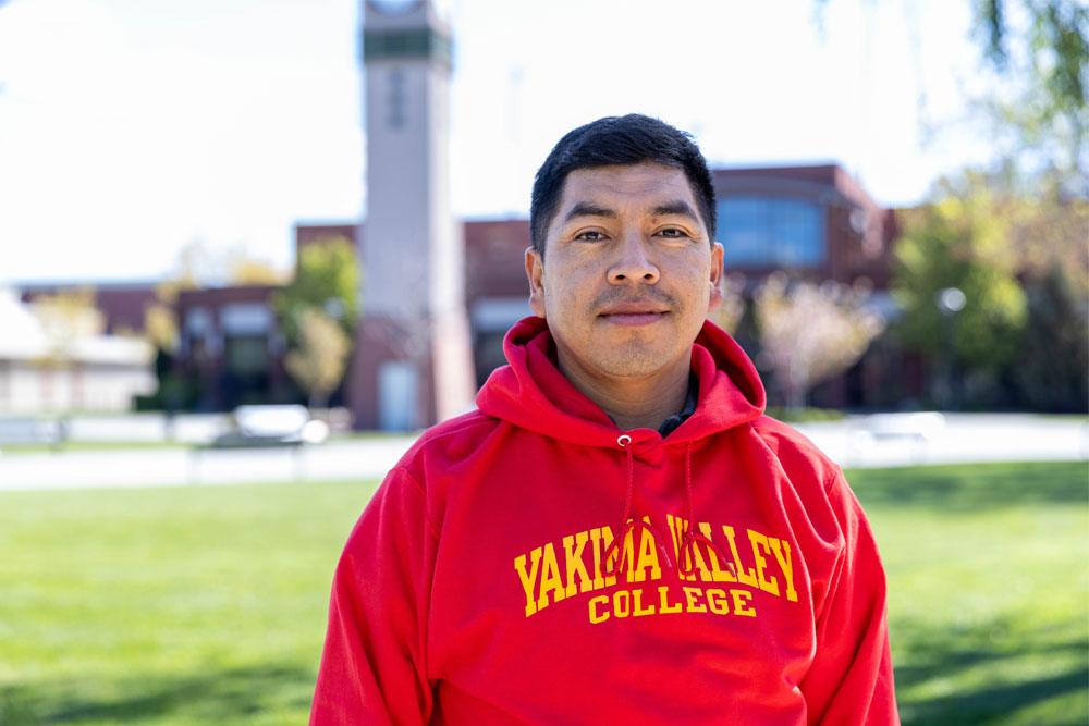 Horacio Hernandez poses for student story picture with YVC clock tower in the background. 