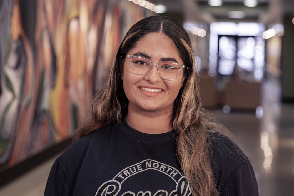 Jasleen Chauhan poses for student story picture in the hallways of a YVC academic building. 