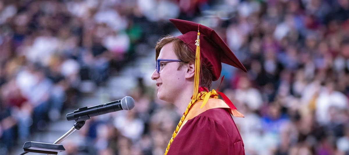 YVC Students gives speech during commencement ceremony wearing cap and gown. 