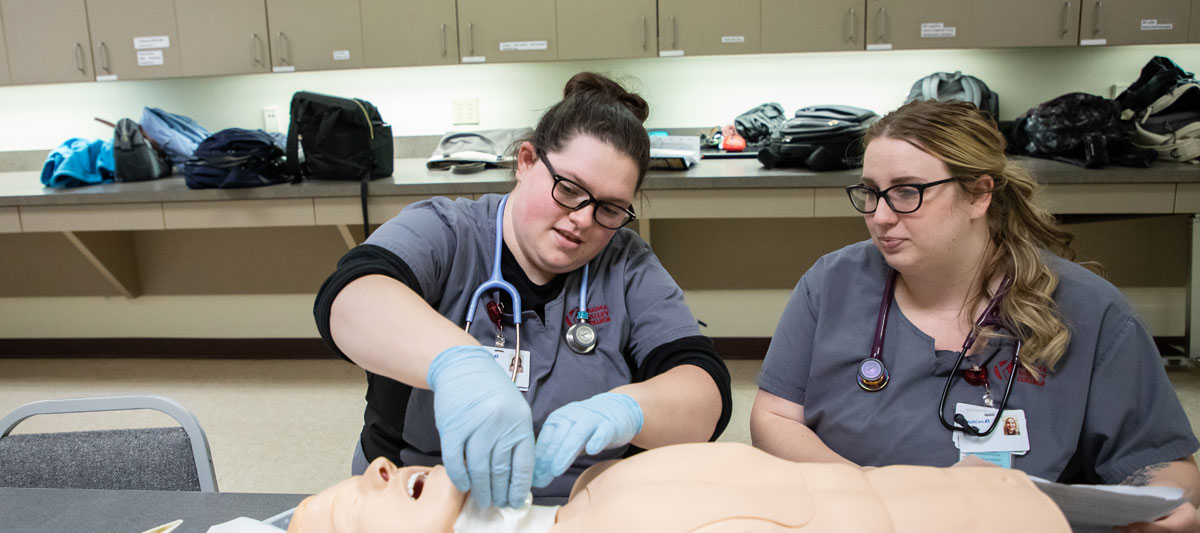 Nursing students work together using a test patient. 