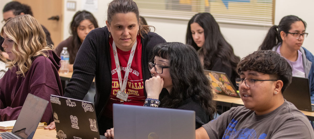 Teacher reads students computer screen while assisting here during class. 