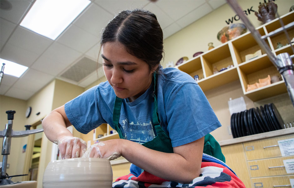 YVC Student working on a pottery wheel in art class.