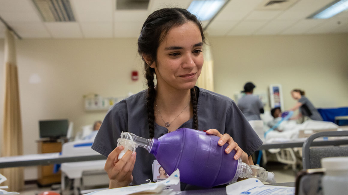 Nursing student works with medical instrument during class. 