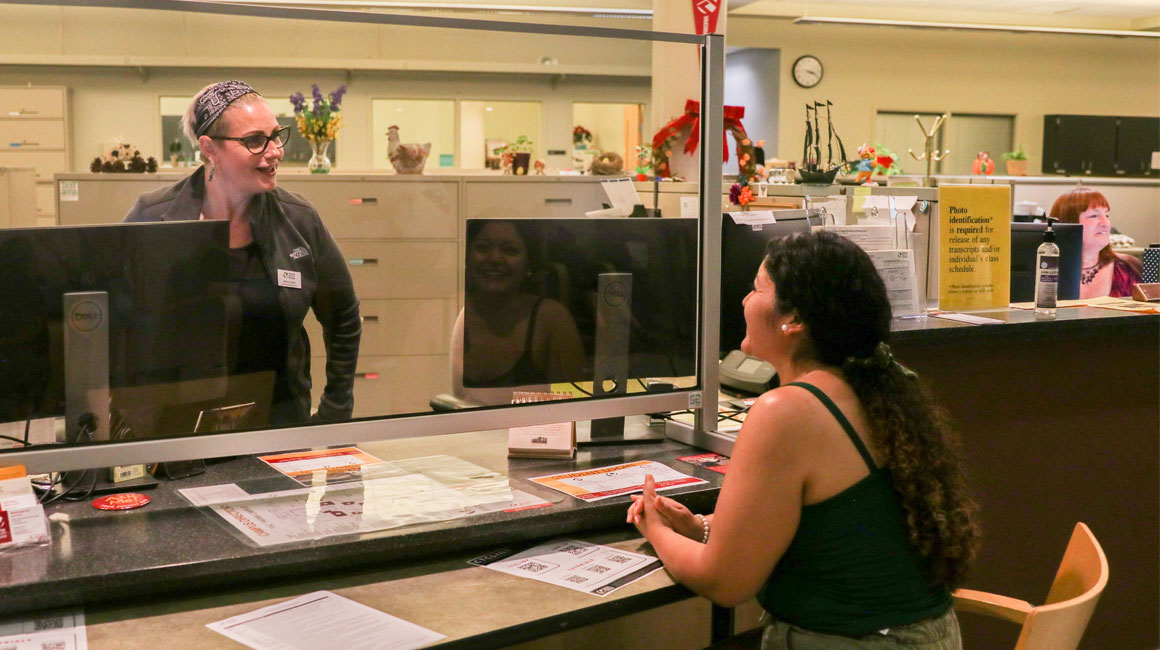 Student talks to YVC employee in an administrative office.