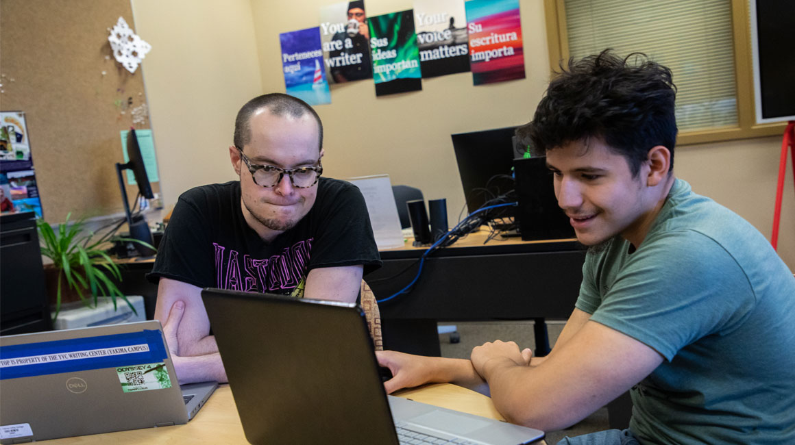 Two students work together on an assignment using a lap top.