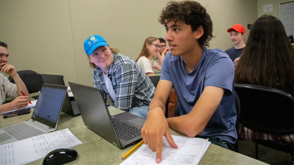 Student points at his paper while asking a question during class. 