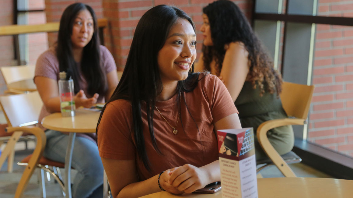 YVC student sits at a table in a YVC common area. 