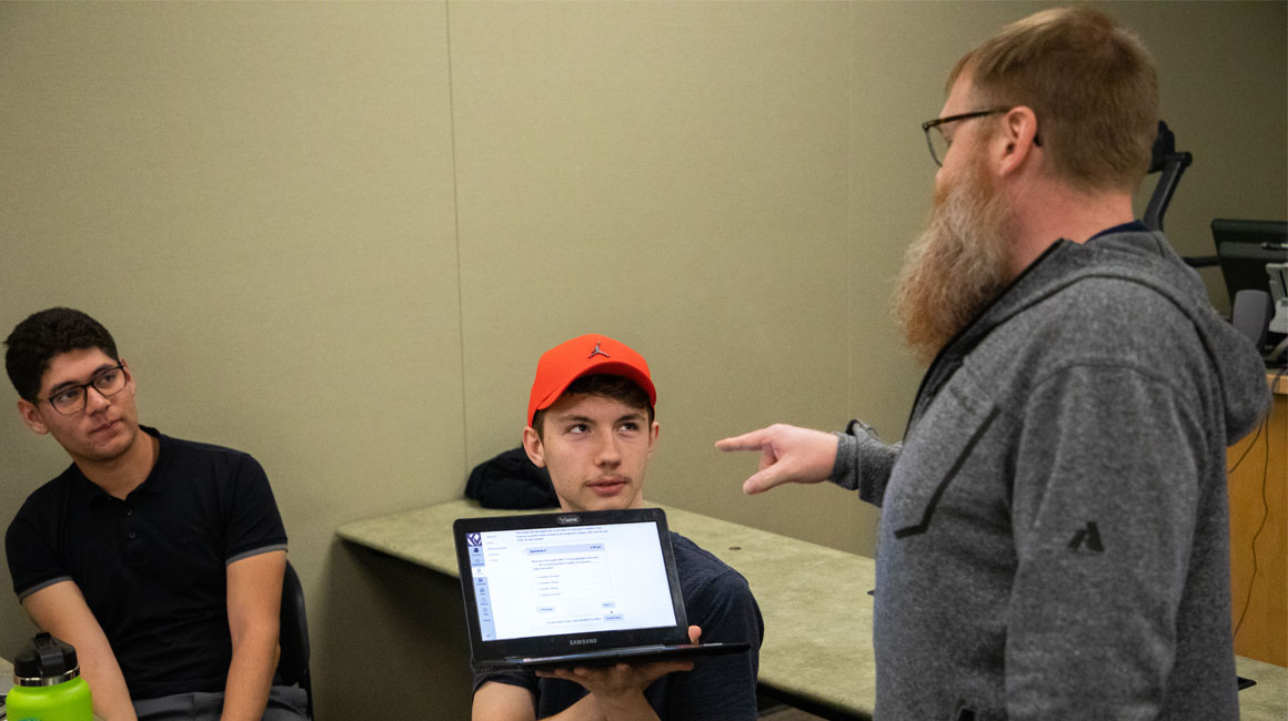 Instructor points to students lap top during class. 